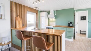 A modern kitchen with a central island, bar stools, and a view of the dining area.