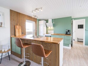 A modern kitchen with a central island, bar stools, and a view of the dining area. - 4 Star Holiday Home in Blavand (Blavand)