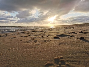 A beach with footprints and rocks, and the sun is setting in the background. - 4 Star Holiday Home in Blavand (Blavand)