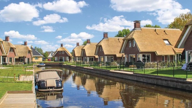 A canal-side row of traditional houses with a boat docked on the left.