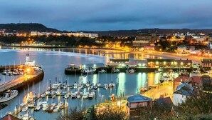 A harbor with boats docked, a lighthouse, and buildings along the waterfront. - Anya’s Lookout - 1 Bedroom Apartment In Scarbourgh (North Yorkshire)