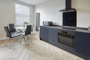 A modern kitchen with a central island, built-in oven, and a black range hood.