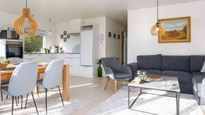 Un soggiorno moderno con un divano grigio, un tavolino in vetro e un'area da pranzo con tavolo e sedie in legno.