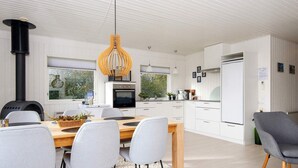 Una cucina moderna con mobili bianchi, un'isola centrale e un piano cottura nero.