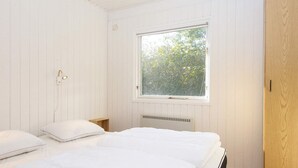 Una camera da letto con due letti, una finestra vista alberi, un armadio in legno e un termosifone sotto la finestra.
