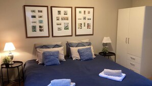 A hotel room with a large bed, two bedside tables, a wardrobe, and three framed pictures on the wall. - 4 Star Holiday Home in Norre Nebel (Norre Nebel)