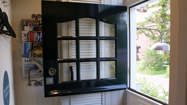 A black-framed door with a grid pattern, a white radiator below, and a view of greenery outside. - Seaside Escape With Comfort (Paesens)