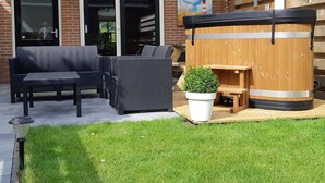 A patio with wicker furniture, a wooden barrel, and a potted plant. - Seaside Escape With Comfort (Paesens)