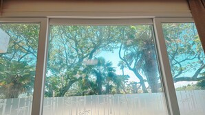 Una ventana con vistas a árboles y una valla con diseño de bambú.
