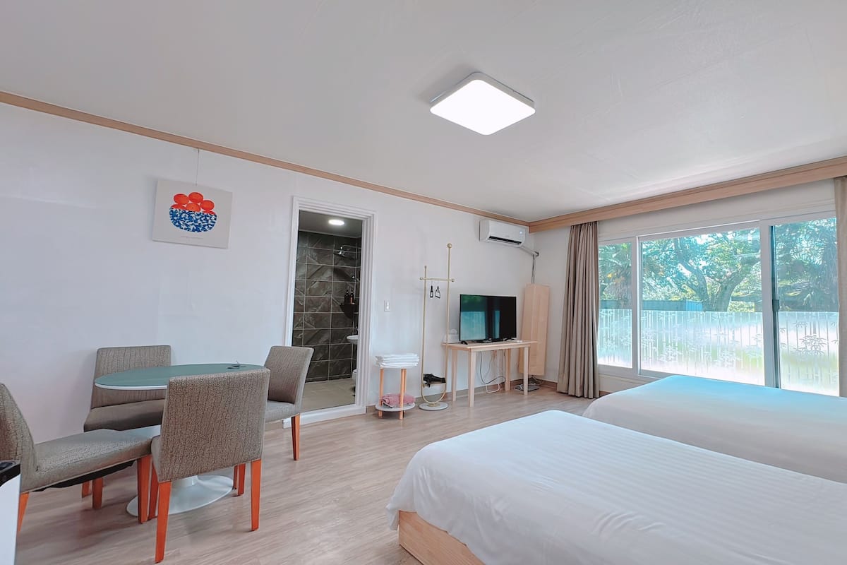 A hotel room with a bed, a desk with a chair, a television, and a bathroom with a shower.