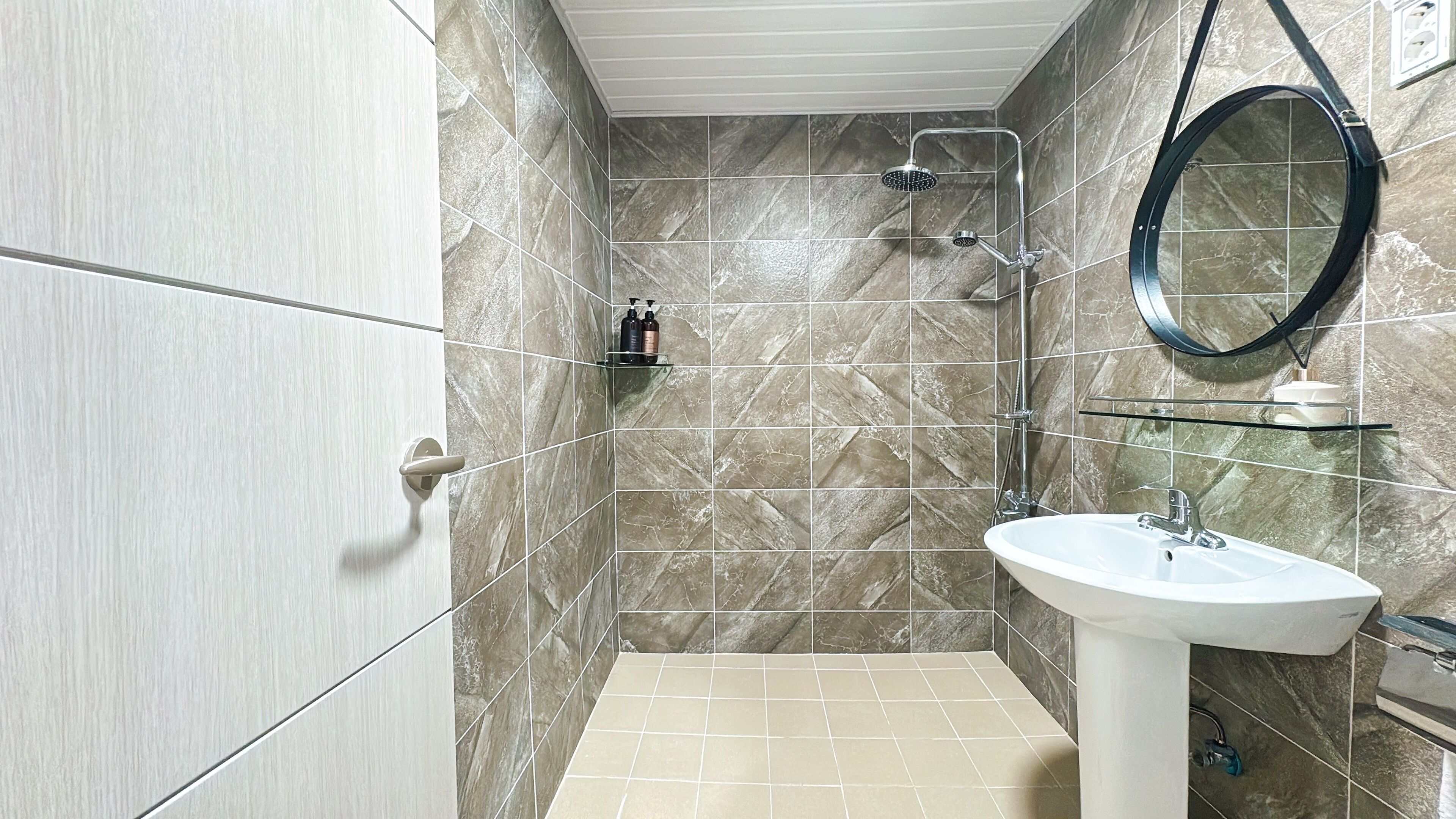 A bathroom with a shower, a sink, and a mirror.