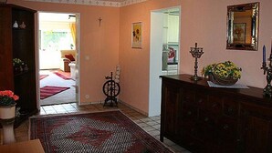 Ett vardagsrum med ett träskåp, en dekorativ matta och en dörröppning som leder till ett annat rum.