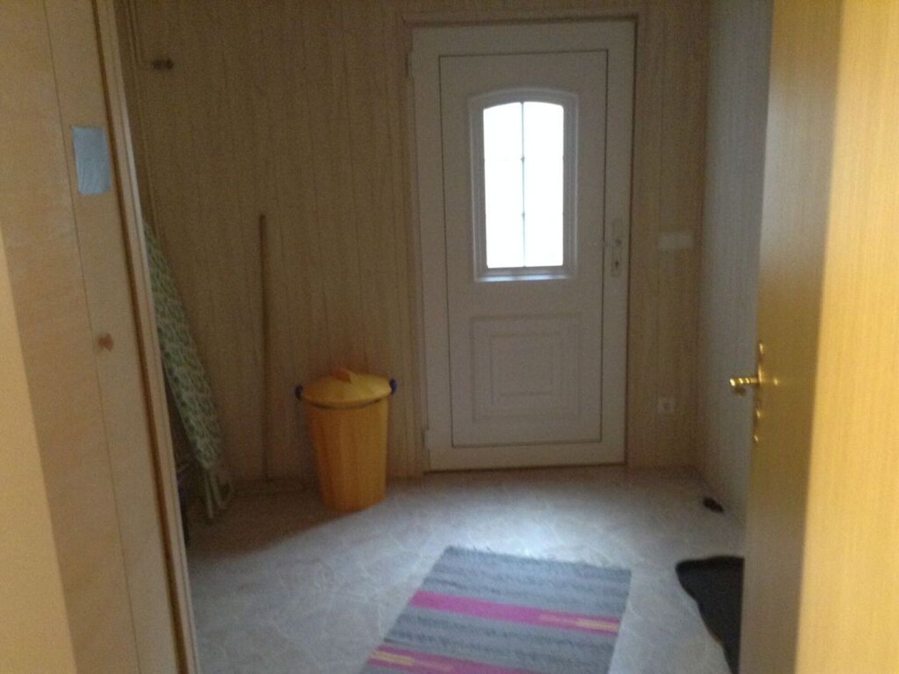 Käytävä, jossa on ovi, ikkuna ja roskakori.