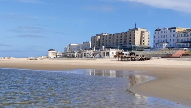 Un hôtel situé en bord de mer, composé de plusieurs bâtiments, doté d’une jetée et bordé d’une plage de sable.