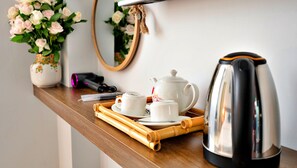 A wooden table with a teapot, cups, and a tray. A mirror hangs on the wall above the table. - HANZ Vivianne Boutique Hotel (Ho Chi Minh City)