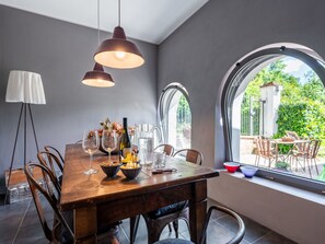 Ein Essbereich mit einem Holztisch, Metallstühlen und einem großen Fenster mit Blick auf Grünflächen.