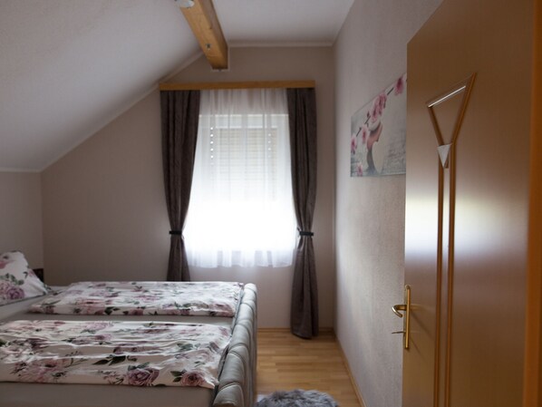 A bedroom with a bed, a window with curtains, a door, and a wall with a picture. - Cosy Apartment in Arnoldstein (Arnoldstein)