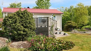 A small wooden cabin with a red roof, a Swedish flag, and a garden with various plants. - 6 Person Holiday Home in Varberg-by Traum (Varberg)
