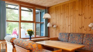 A wooden cabin interior with a bench, sofa, and table. - 6 Person Holiday Home in Vaeggerlose (Vaeggerlose)