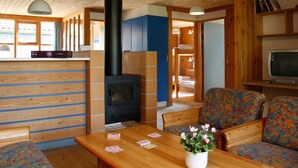 A cozy cabin interior with a wood-burning stove, a sofa, a table with playing cards, and a television. - 6 Person Holiday Home in Vaeggerlose (Vaeggerlose)