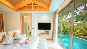 Une chambre moderne dotée d’un grand lit, d’un téléviseur à écran plat et d’une piscine intérieure fermée par des parois de verre.