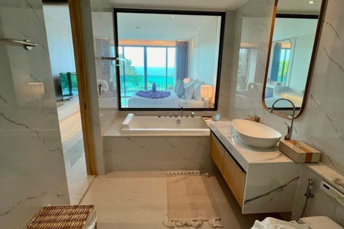 A modern bathroom with a large bathtub, a freestanding sink, and a large mirror.