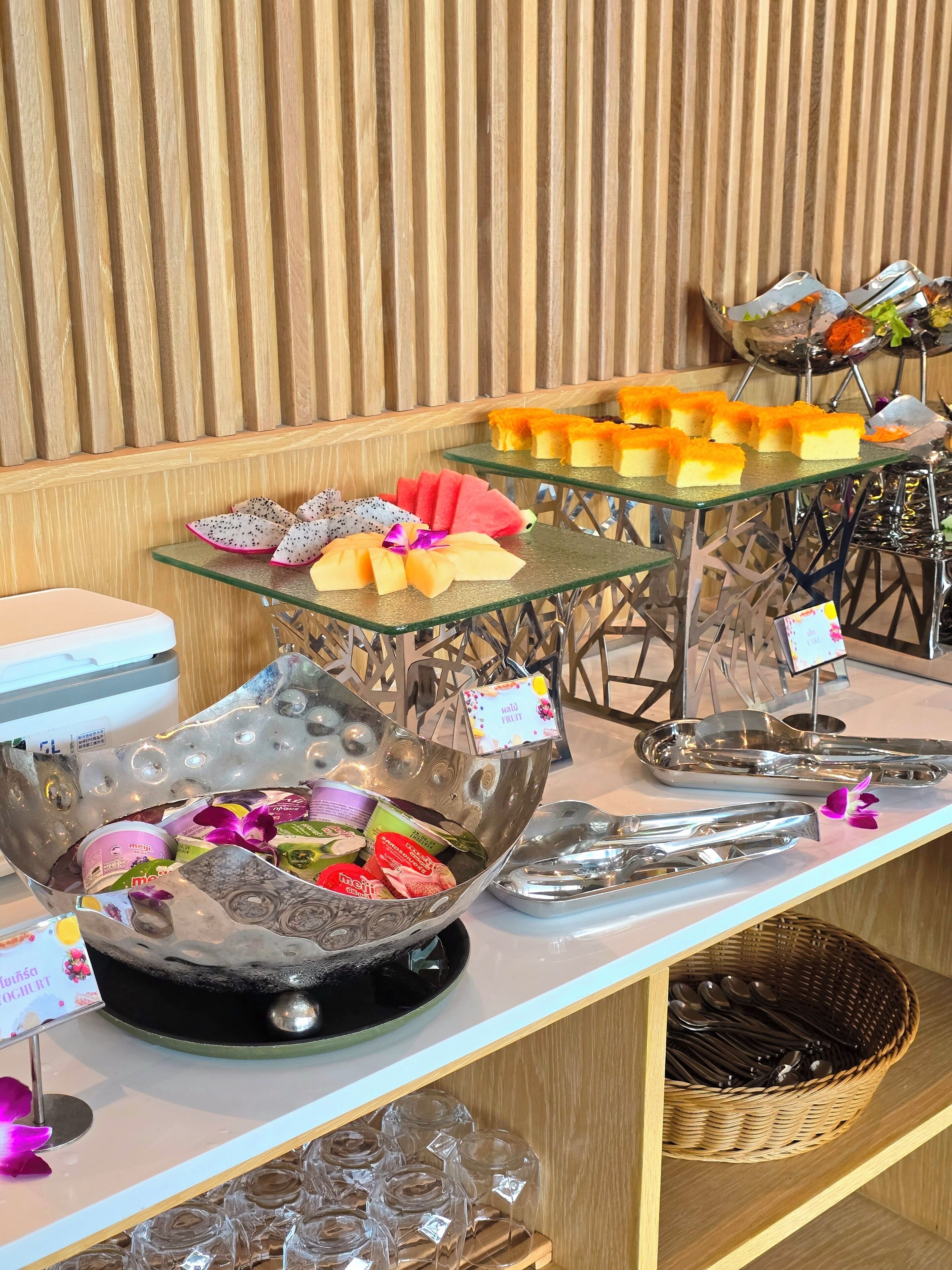 A buffet with various food items, including fruit, yogurt, and desserts.