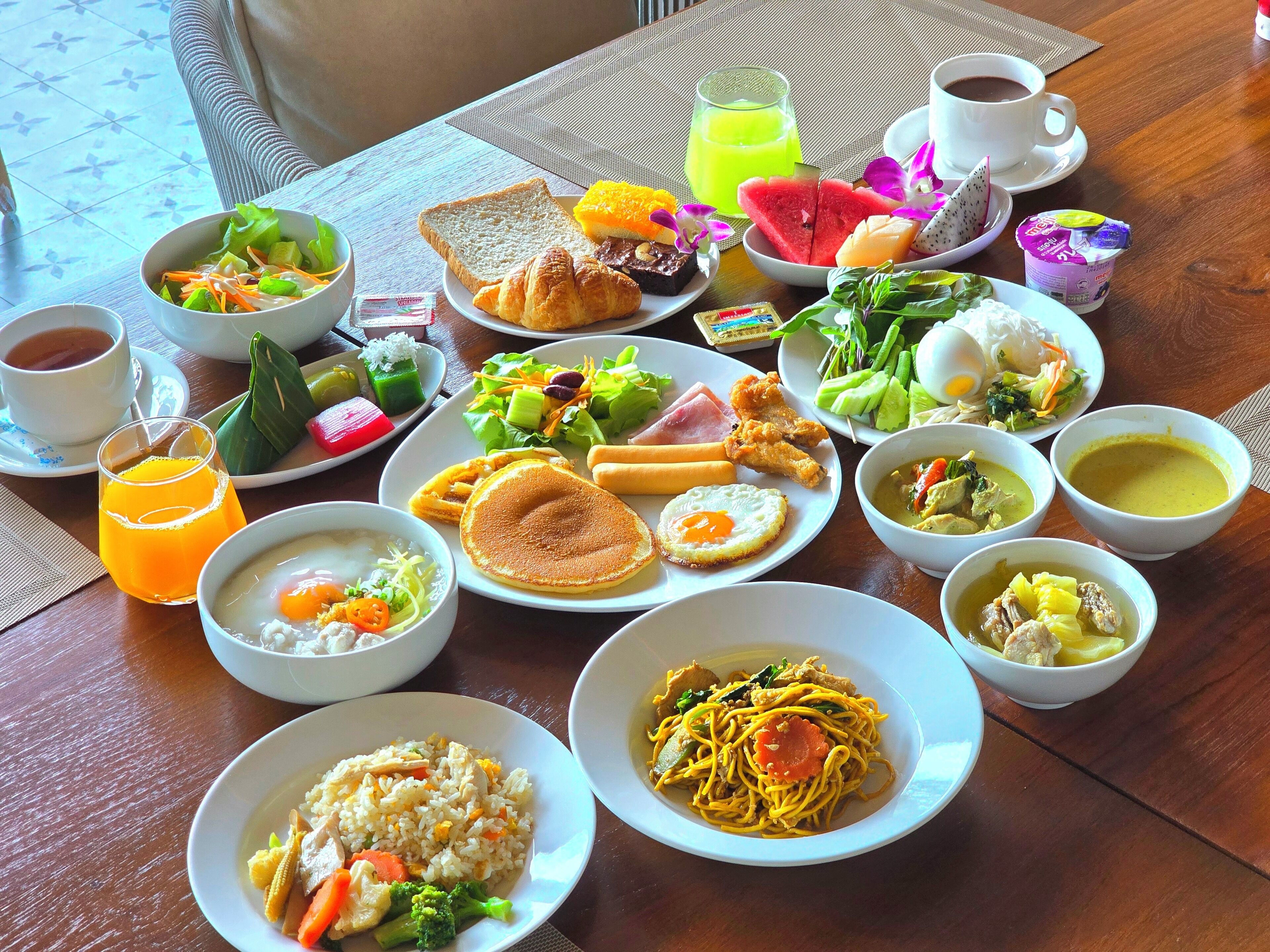 A table set with various breakfast dishes including eggs, pancakes, and soup.