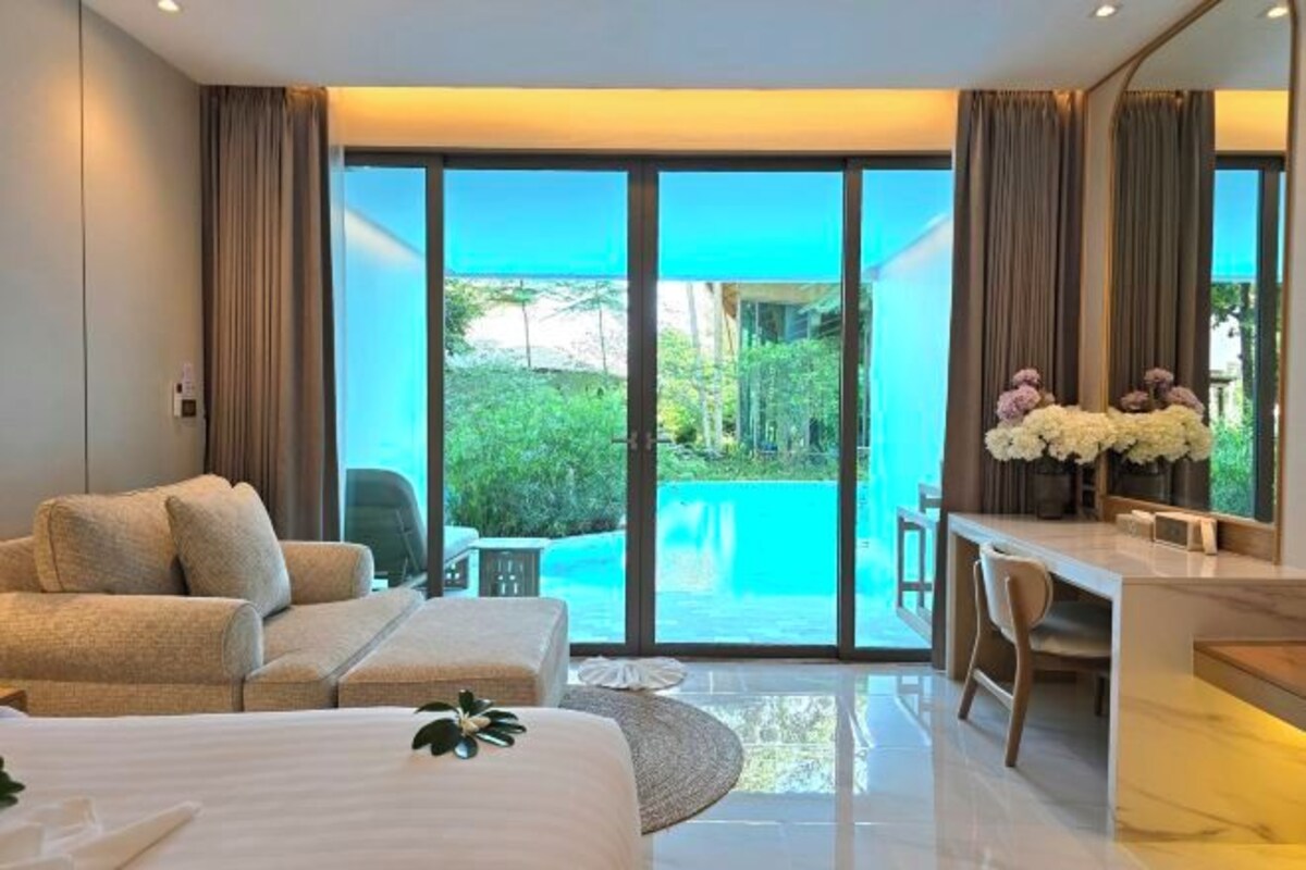 A modern hotel room with a bed, a desk, and a view of a swimming pool.