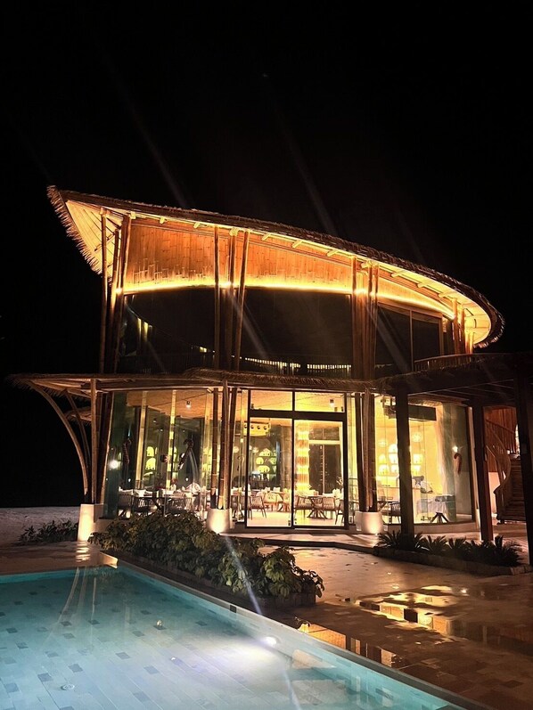 A modern hotel with a pool, large glass windows, and a covered outdoor area. - Luxtalay Khanom Hotel (Khanom)