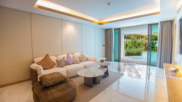 A modern living room with a sofa, ottoman, and coffee table, a glass door leading to a pool area, and a wooden side table.