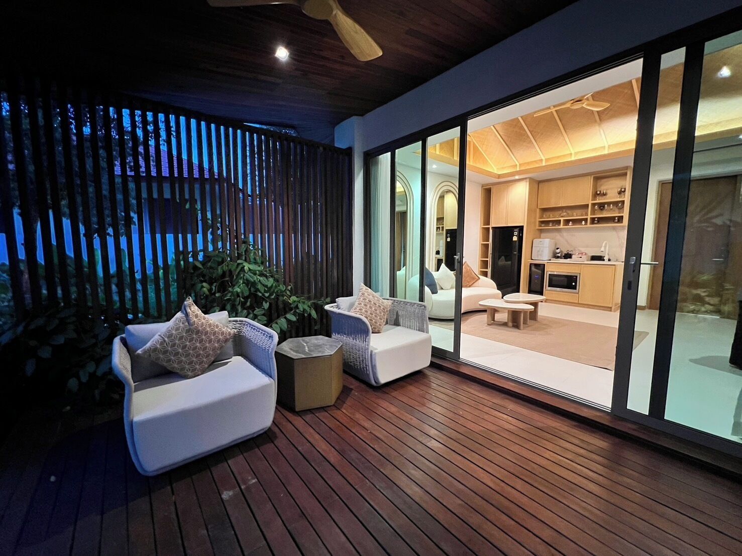 Un área de estar moderna al aire libre con mobiliario de mimbre y una terraza de madera.