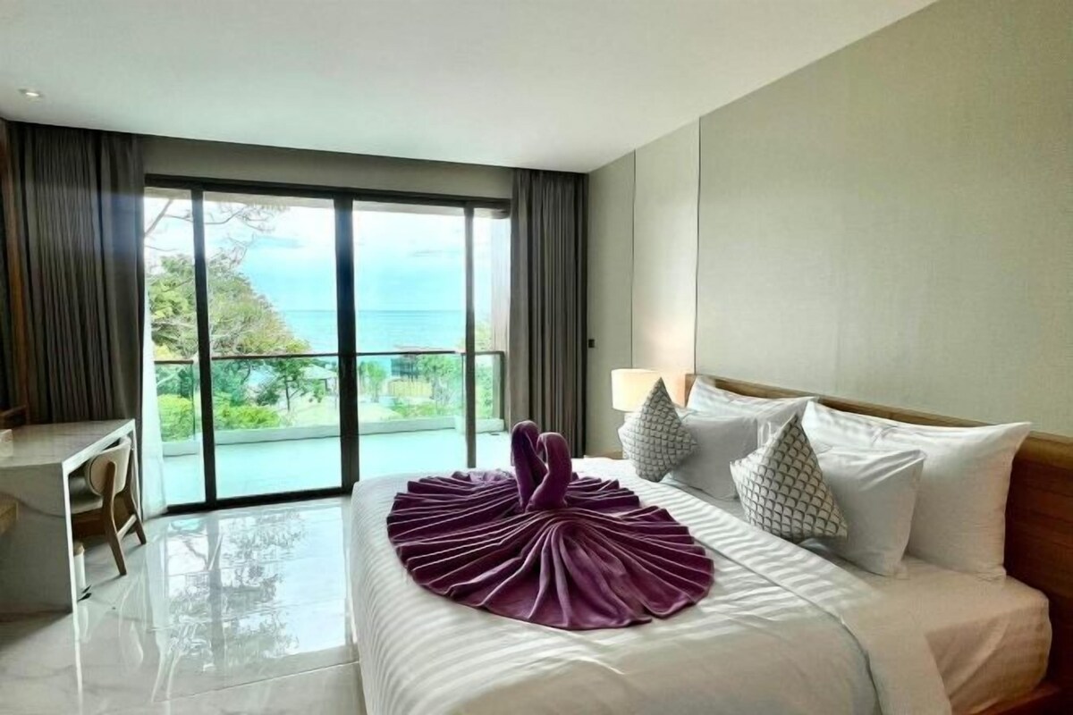 Habitación de hotel con una cama grande, un escritorio y vista al mar.
