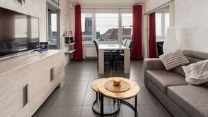 Un salon moderne avec un téléviseur à écran plat, une table à manger et un canapé.
