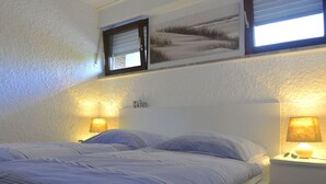A bedroom with a bed, two bedside lamps, and a wall-mounted picture. - Apartment Albatros 14 (Butjadingen)