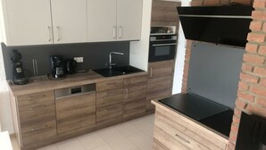 A modern kitchen with wooden cabinets, a black countertop, a coffee machine, and a brick oven. - Apartment Albatros 14 (Butjadingen)