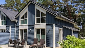 A two-story house with a patio area featuring a table and chairs. - Strandhus Baabe Haus 3 (Ostseebad Baabe)