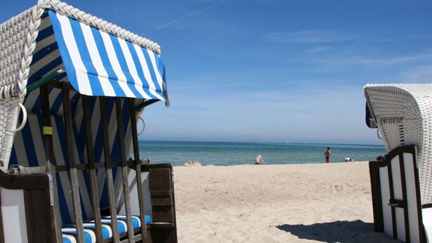 A beach with a striped beach chair and a white beach umbrella. - Strandhus Baabe Haus 3 (Ostseebad Baabe)