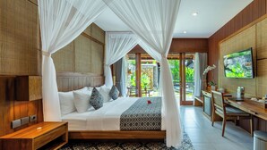 A bedroom with a bed, bedside table, TV, desk, and chair. - PURI ANDONG VILLAS (Ubud)