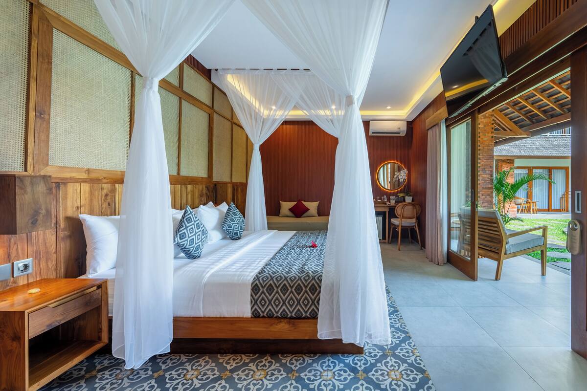 Un dormitorio con cama con dosel, paredes de madera, piso estampado y vista al exterior.
