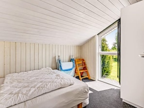 Une chambre à coucher avec un lit, une fenêtre et une échelle en bois.