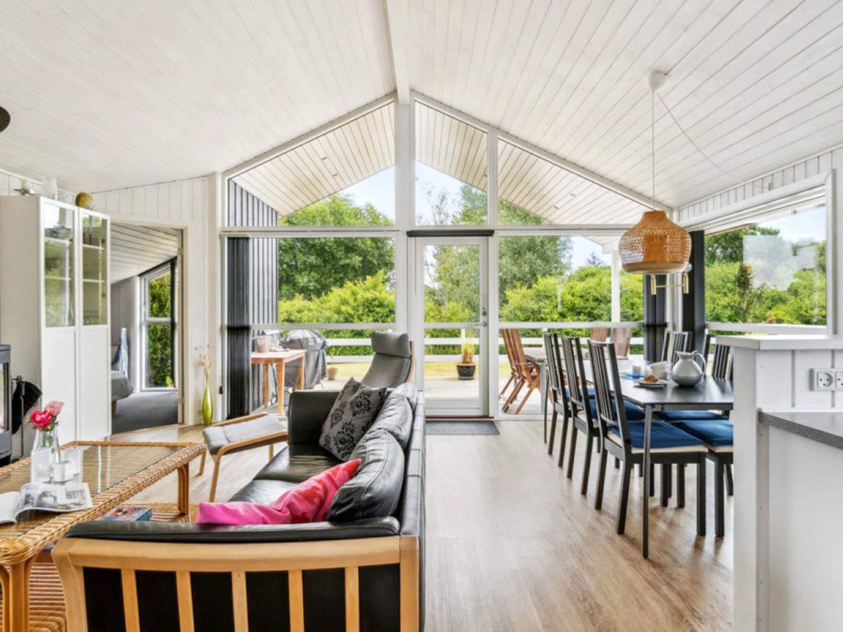 A spacious room with a large sliding glass door leading to an outdoor area, a seating area with a sofa and chairs, and a dining table with chairs.
