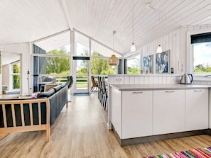A modern kitchen with white cabinets, a wooden countertop, and a view of the outdoors.