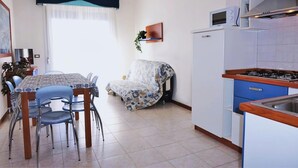 Une cuisine compacte comprenant un coin repas, un four à micro-ondes, une cuisinière à gaz et un réfrigérateur.
