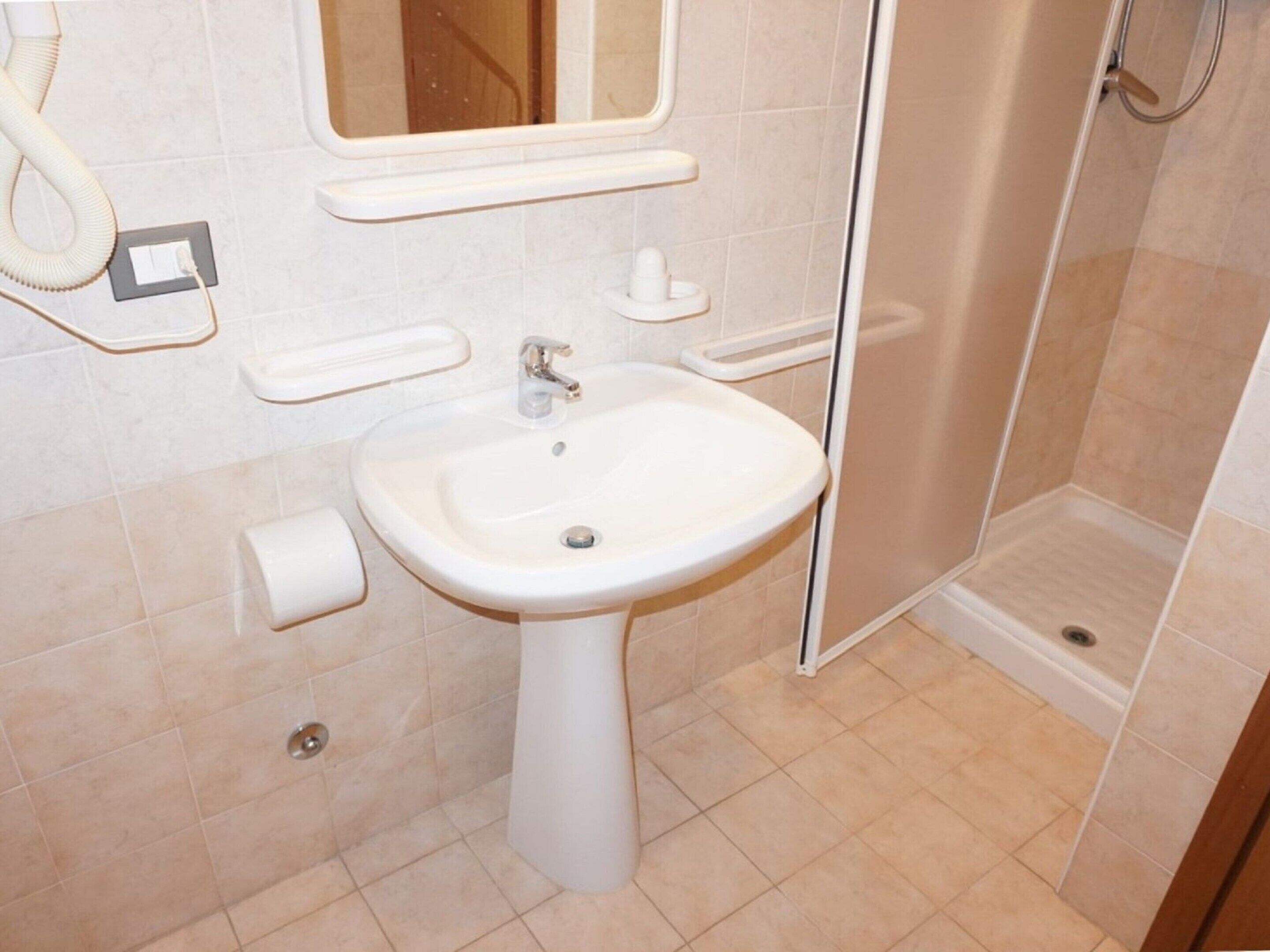 A bathroom with a sink, mirror, towel rack, and shower.