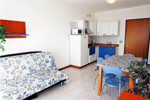 A compact living space with a sofa, dining table, chairs, a kitchenette, and a door. - Seaside Sunny Stay With Solarium (Caorle)