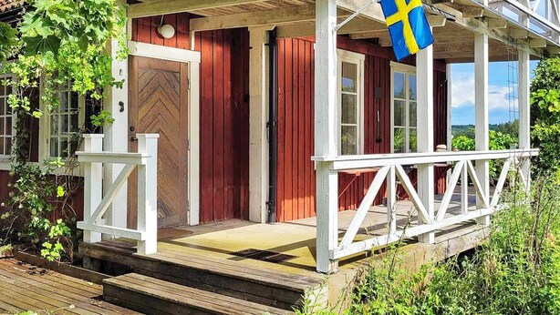 Una casa di legno con veranda, una bandiera e un'apertura.