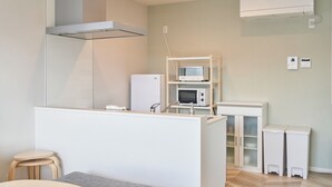 A modern kitchen with a microwave, refrigerator, and built-in oven. There is a small wooden stool and a white cabinet with glass doors. - Mt Fuji Resort Club -Relax- (Fujikawaguchiko)