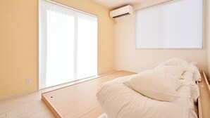 A bedroom with a bed, a window with blinds, an air conditioning unit, and a wooden floor. - Mt Fuji Resort Club -Relax- (Fujikawaguchiko)