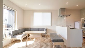A modern kitchen with a built-in island, a seating area with a bench and a sofa, and a large window providing natural light. - Mt Fuji Resort Club -Relax- (Fujikawaguchiko)
